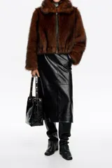 Chaqueta corta de corte globo confeccionada en pelo sintético color marrón, con cierre frontal de cremallera metálica y cuello camisero amplio. Presenta manga larga recta y bolsillos laterales de vivo.