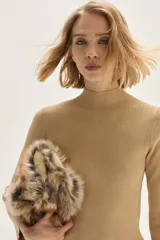 Polera de tejido de punto acanalado en color beige, con cuello alto y mangas largas. Presenta un sutil acabado brillante gracias a sus detalles en lurex.