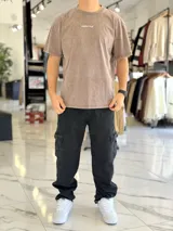 Remera oversize de efecto lavado color marrón, con diseño gráfico estampado en la espalda que incluye texto y una estrella estilizada.