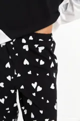 Pijama compuesto por una remera de manga larga blanca y un pantalón negro con estampado de corazones blancos. El pantalón cuenta con cintura elástica para mayor comodidad.