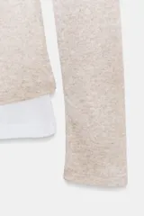 Camiseta de manga larga gris melange con cuello redondo y diseño asimétrico que simula una doble camiseta, con una capa inferior blanca visible en el cuello y el bajo.