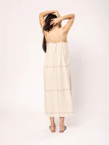 Vestido largo color crudo de lino, con silueta recta, escote en V, breteles anchos, detalle de elástico en la espalda y tajos laterales.