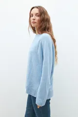 Sweater de punto en color celeste, con cuello redondo, mangas largas y puños acanalados. Presenta un diseño de corte holgado con costuras verticales decorativas en el frente.