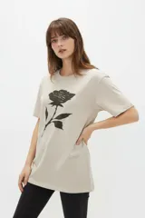 Remera de manga corta color blanco, de corte holgado con cuello redondo a la base y estampado frontal en tono bordó de un gato y un ovni en un paisaje desértico.