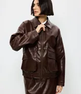 Campera de cuero sintético color marrón oscuro, con cuello clásico, cierre frontal metálico, dos bolsillos frontales amplios con solapa y ruedo con elástico.