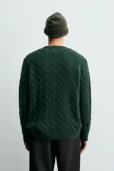 Jersey de punto con diseño de trenzas verticales, cuello redondo y manga larga. Presenta un ajuste regular y acabados en rib en cuello, puños y ruedo.