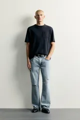 Jeans flare fit de denim negro, tiro medio, ajustados arriba y con botamanga acampanada. Cuentan con cinco bolsillos, lavado efecto gastado y bajo con acabado irregular. Cierre frontal con cremallera y botón.