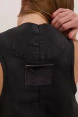 Chaleco de denim con proceso de encuerado, color negro, con escote en V, cierre frontal con botones y bolsillos delanteros con solapa.