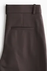 Pantalón tobillero de color marrón oscuro, corte recto y ajustado, con cintura estándar y bolsillos al bies.