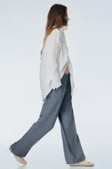 Pantalón sastrero gris de tiro alto, con pliegues marcados al frente y piernas anchas y rectas.