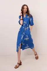 Vestido midi azul con estampado floral blanco, cuello en V, mangas cortas abullonadas y cierre frontal de botones. Incluye un lazo ajustable para la cintura.
