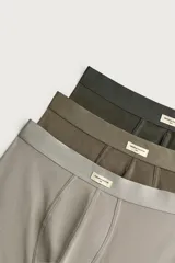 Pack de tres calzoncillos tipo bóxer de tejido elástico con acabado aterciopelado, en tonos neutros gris, marrón y verde oscuro, con cintura elástica.