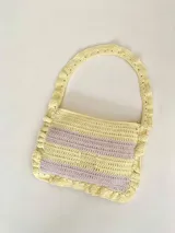 Cartera tipo shoulder bag tejida a crochet en hilo de algodón, con diseño a rayas en tonos de rojo y rosado, y detalles de volados en los bordes y la manija de hombro.