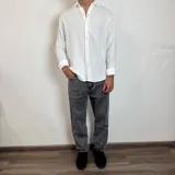 Camisa de manga larga confeccionada en lino, color blanco, con cuello clásico y cierre frontal de botones.