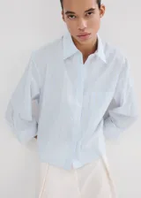 Camisa de corte recto y diseño a rayas con cuello camisero, manga larga con puños abotonados y cierre delantero con botones.
