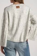Sweater de punto con textura de ochos, color gris melange con motas oscuras, cuello redondo y mangas largas con terminación acampanada.