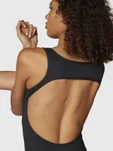 Enterito largo de una pieza color negro, con tirantes anchos, escote redondo y piernas con corte ligeramente acampanado. Confeccionado en tejido elástico con costuras anatómicas que se ajustan al cuerpo.