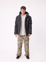 Campera técnica de invierno marca Rusty, color negro, con capucha ajustable, cierre frontal con solapa y bolsillos laterales. Presenta logo de la marca estampado en blanco en la manga y en el pecho.