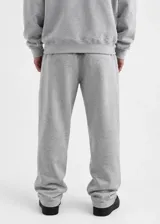 Pantalón de jogging gris melange, de corte holgado y diseño baggy. Cuenta con bolsillos laterales y el logo impreso en la pierna izquierda.