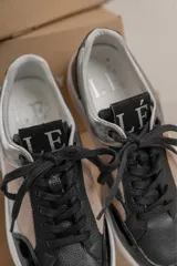 Championes urbanos con diseño de paneles en tonos verde oliva, negro y gris. Presentan una combinación de texturas que incluye cuero liso, gamuza y un panel con estampado de piel de serpiente en el talón. Cuentan con cordones negros y una suela de plataforma blanca con textura acanalada.