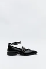 Zapato tipo zueco negro charol con punta fina, doble tira con hebillas metálicas y pulsera al tobillo con tachas.