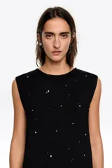 Musculosa negra de corte recto con escote redondo y aplicación de piedras brillantes dispersas por toda la prenda.