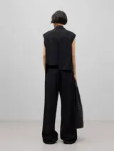 Pantalón negro de corte palazzo, confeccionado en mezcla de lana merino. Presenta cintura alta con cinturilla elástica, bolsillos italianos laterales y bolsillos de vivo en la espalda.