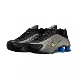 Championes Nike Shox R4 con parte superior en negro y plateado, diseño futurista con amortiguación de columnas azules en el talón y swoosh en tono amarillo.