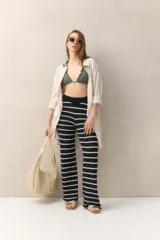 Pantalón largo de tejido de punto color crudo con rayas horizontales negras, corte ajustado y cintura alta.