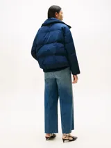 Campera acolchada de corte regular con cuello chimenea, cierre frontal a presión con botones dorados y bolsillos laterales. Presenta un diseño repelente al agua con relleno de plumón y escudo de la marca bordado en el pecho.