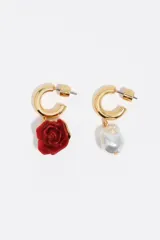 Pendientes de aro dorados con diseño asimétrico, uno con dije de rosa roja en resina y el otro con dije de perla barroca. Cierre de presión.