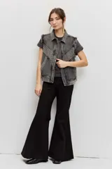 Campera de jean color gris con efecto acid wash, corte clásico y cierre frontal de botones metálicos. Presenta cuello camisero, bolsillos ribeteados y está decorada con apliques de tachas plateadas en el cuello, el canesú frontal, los bordes de la botonera, los bolsillos y el ruedo.