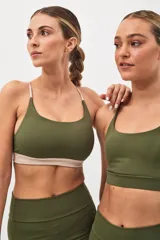 Top deportivo verde militar con espalda cruzada de doble tira y banda inferior color beige. Incluye almohadillas removibles.