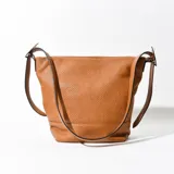 Cartera tipo tote de cuero sintético color marrón con textura granulada y perforaciones. Tiene correa de hombro ajustable y cierre superior con botón imantado.