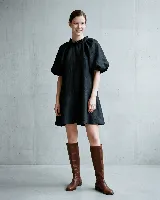 Vestido corto de lino, color negro, con cuello redondo fruncido, mangas cortas abullonadas tipo ranglan y corte evasé con volado en el ruedo.
