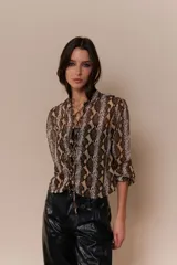 Blusa roja con estampado de piel de serpiente, escote en V con cordones y mangas 3/4 con puños elásticos.