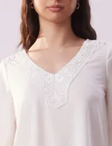 Blusa color blanco con escote en V y aplique de crochet.