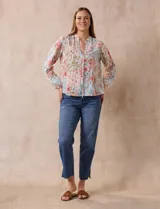 Blusa de gasa plisada con estampado floral en tonos rosas y celestes. Presenta cuello a la base con escote en V y lazo de ajuste frontal, mangas largas con puños elásticos y corte recto.