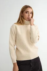 Polera de tejido de punto con cuello alto y diseño de textura en zigzag. Presenta puños y ruedo acanalados.