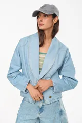 Chaqueta corta de jean color crudo, de silueta holgada, con mangas ranglan, solapas anchas y detalles de costuras pespunteadas a contratono.