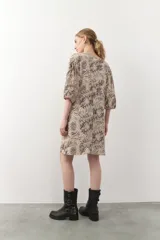 Vestido corto con estampado animal print en tonos beige y negro. Tiene mangas tres cuartos con elástico, cut-out en el frente y lazo.