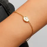 Pulsera dorada con cadena fina y dije ovalado con el signo zodiacal de Piscis.