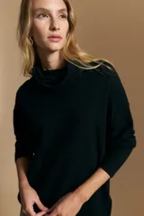 Polera de tejido de punto color naranja con cuello alto de caída relajada y diseño de líneas en relieve. Presenta una silueta holgada con hombros caídos y mangas largas.
