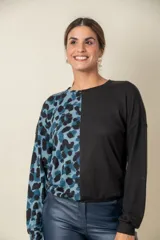 Buzo de manga larga con cuello redondo, combinado en dos tonos: negro liso en la mitad derecha y estampado animal print blanco y negro en la mitad izquierda.