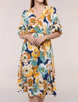 Vestido midi de calce holgado y caída fluida con escote en V cruzado, cintura elastizada fruncida y mangas cortas con volados superpuestos. Cuenta con un diseño estampado de flores grandes en tonos amarillo, blanco, azul marino y verde.
