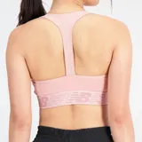 Top deportivo New Balance color rosa con espalda cruzada y logo de la marca en la banda inferior.