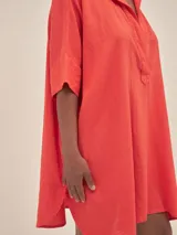Túnica corta de lino color naranja, con cuello camisero y escote en V. Mangas cortas y corte holgado.