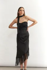 Vestido midi sin mangas color turquesa, con escote strapless y detalle de nudo frontal. El ruedo presenta un corte asimétrico con flecos negros largos.