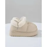 Pantuflas botitas color tostado con diseño acolchado y plataforma, forradas con corderito sintético blanco en el interior y el cuello. Cuentan con una pequeña etiqueta decorativa en el lateral.