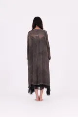 Vestido camisero largo, color gris oscuro con efecto desgastado/lavado. Presenta cuello camisero, botones frontales y mangas largas. El bajo es irregular y se superpone con un forro o capa de tela negra con terminación de encaje o volado.